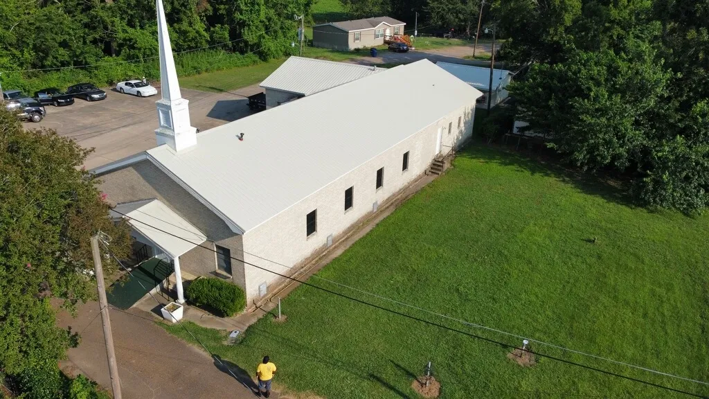 Aerial view of a church with a finished white metal roof